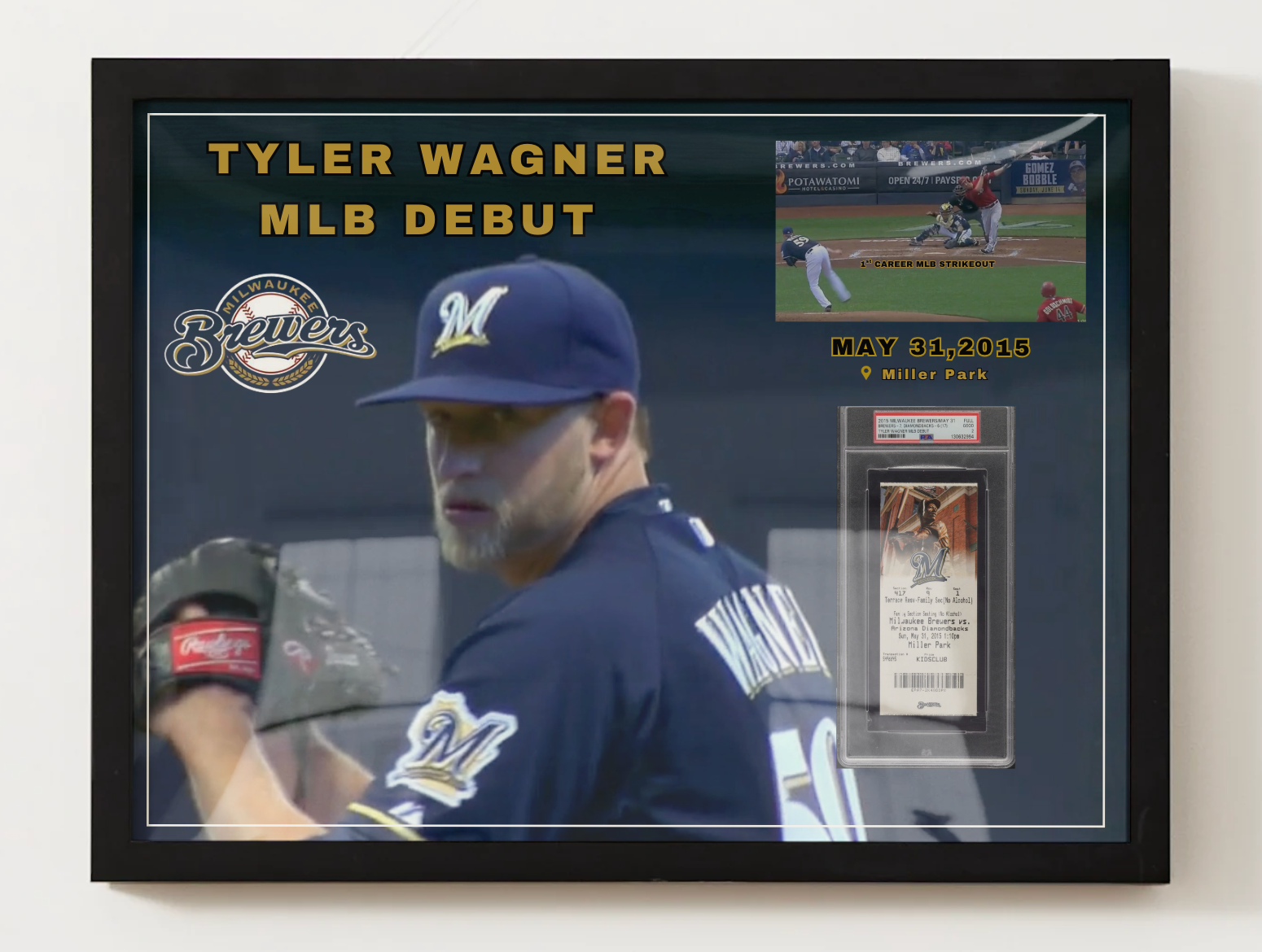 A framed Tyler Wagner Milwaukee Brewers MLB debut memorabilia display on a light wall. The black-framed collage features a large photo of Wagner in his navy Brewers uniform, gold text reading 'TYLER WAGNER MLB DEBUT,' the Brewers logo, a small in-game action inset, and a PSA-graded card inside a clear display case.
