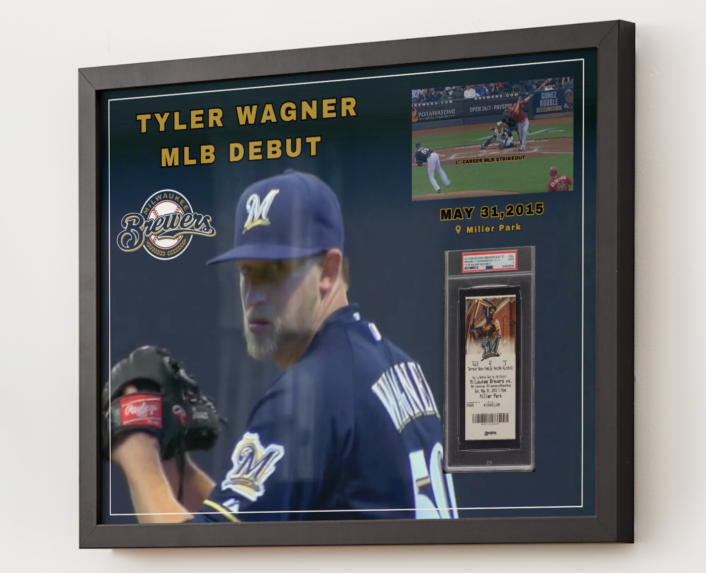 A framed baseball memorabilia display featuring a large photo of Tyler Wagner in a Milwaukee Brewers uniform, gold text reading 'TYLER WAGNER MLB DEBUT,' a small action inset, the Brewers logo, and a PSA-graded card mounted on a dark navy background inside a black frame.